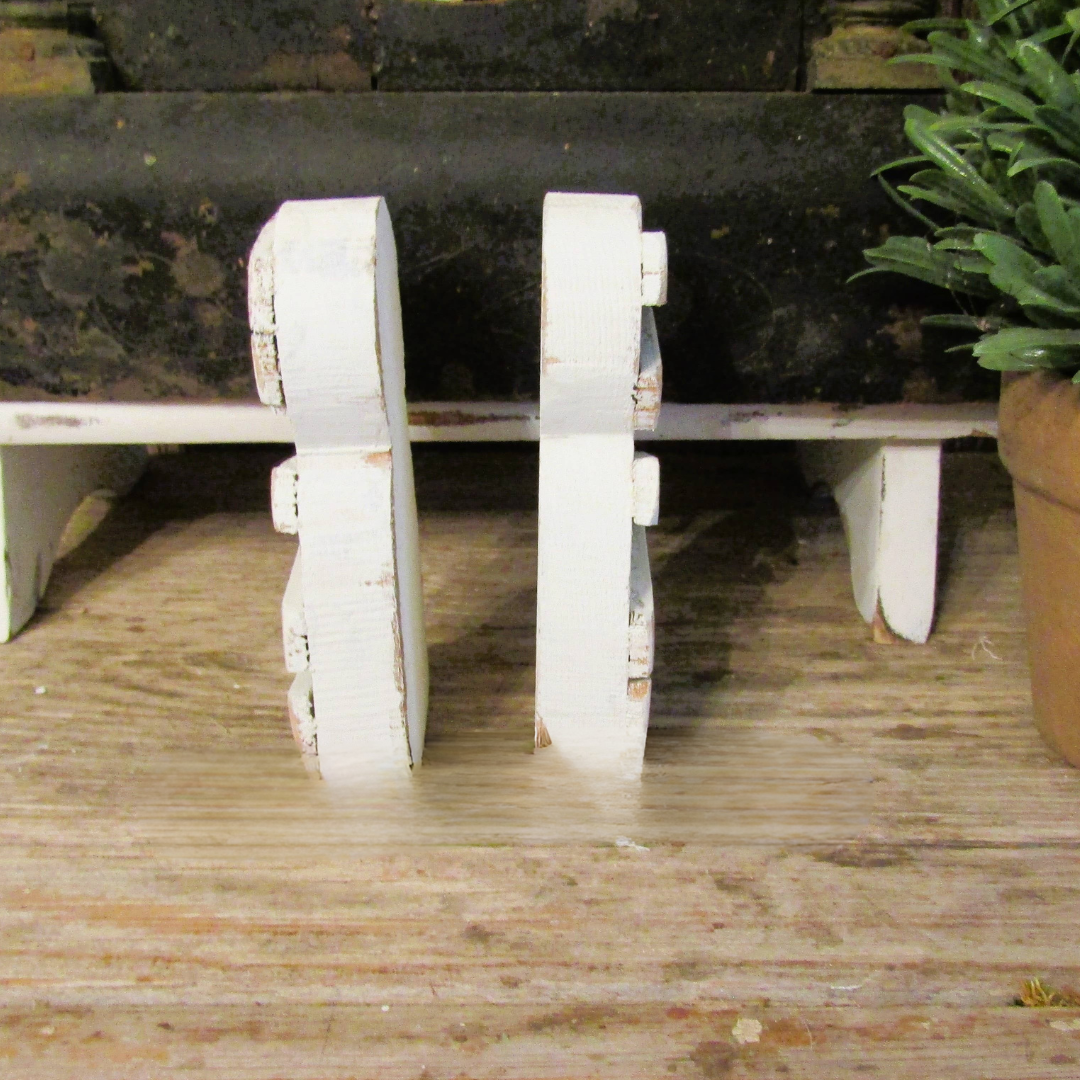 Back view of two small wood mummies showing plain white painted backs and that they stand on their own
