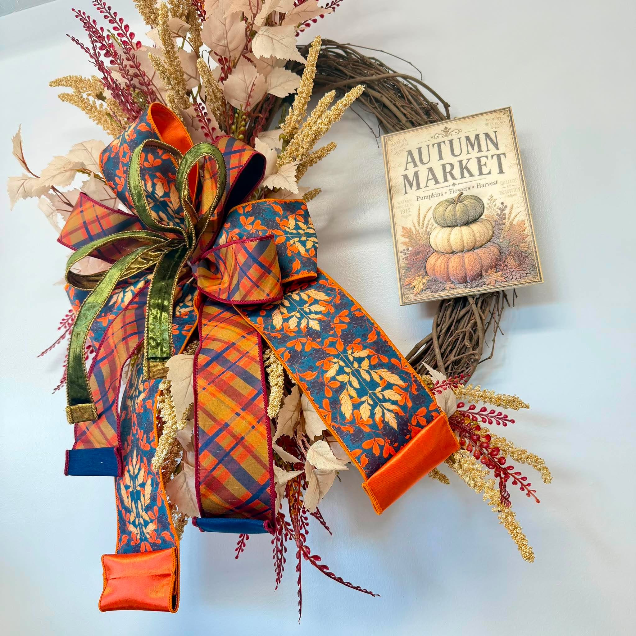 Fall grapevine wreath with a layered orange plaid, teal leaf print and green velvet ribbon bow