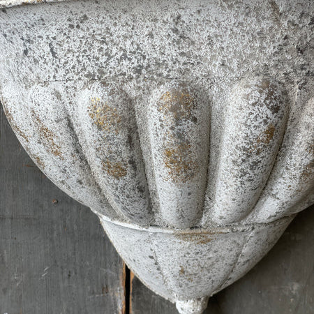 Decorative metal wall bracket with ribbed design on a wooden background
