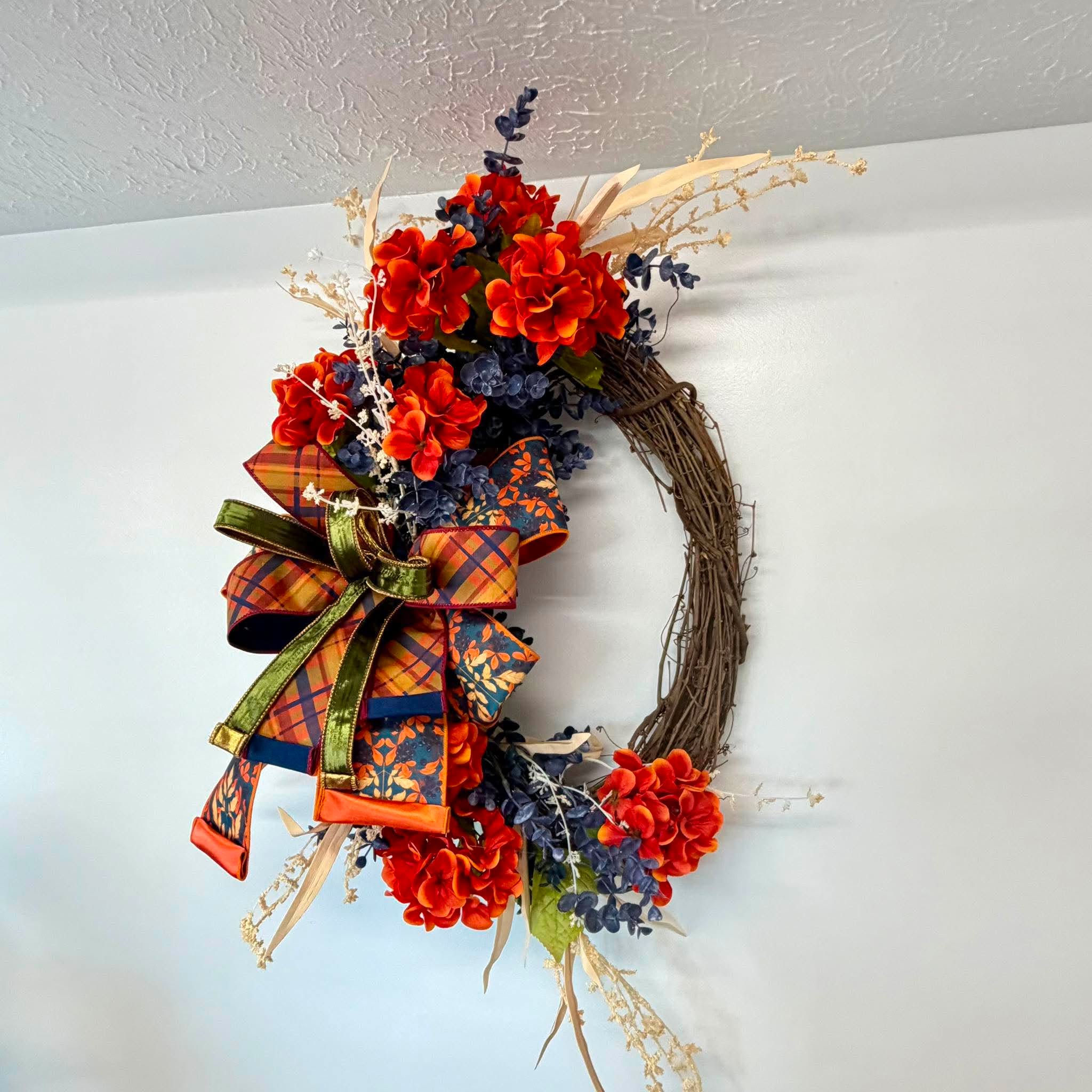 Side view of the orange hydrangea fall grapevine wreath and its layered plaid ribbon bow