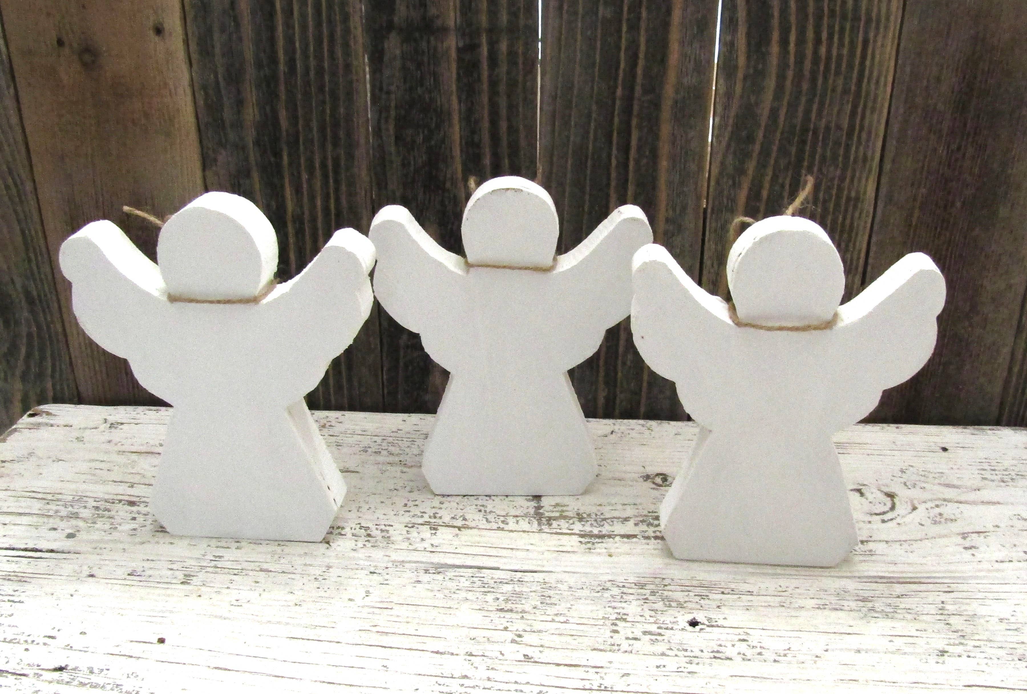 Back view of three wood angels showing they are painted white on all sides