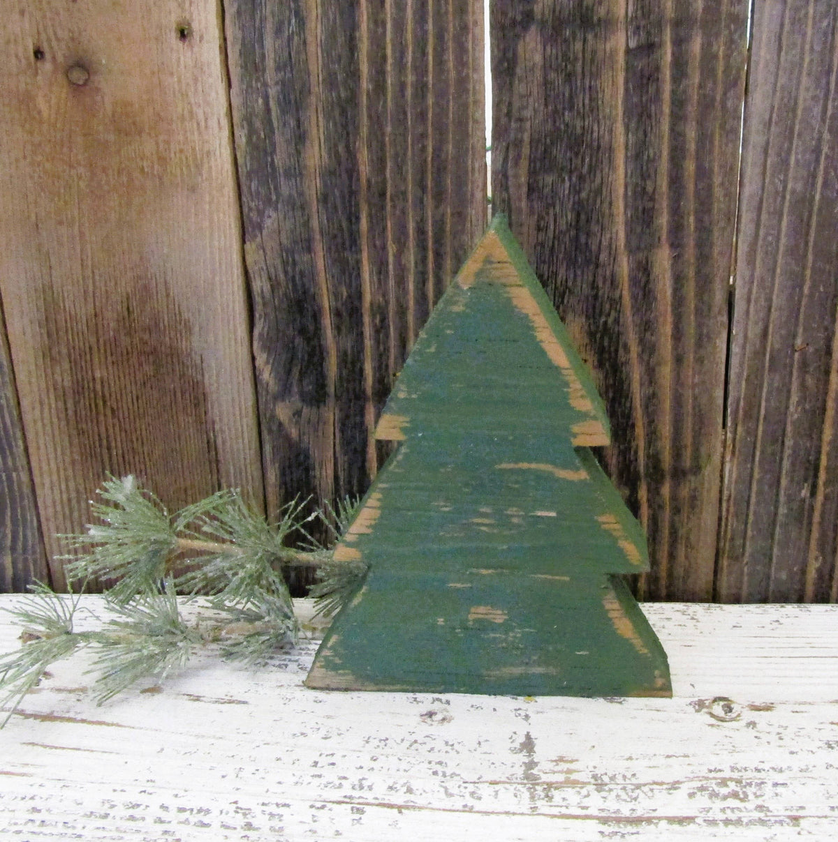 Green distressed wood Christmas tree shelf sitter standing on a white farmhouse shelf