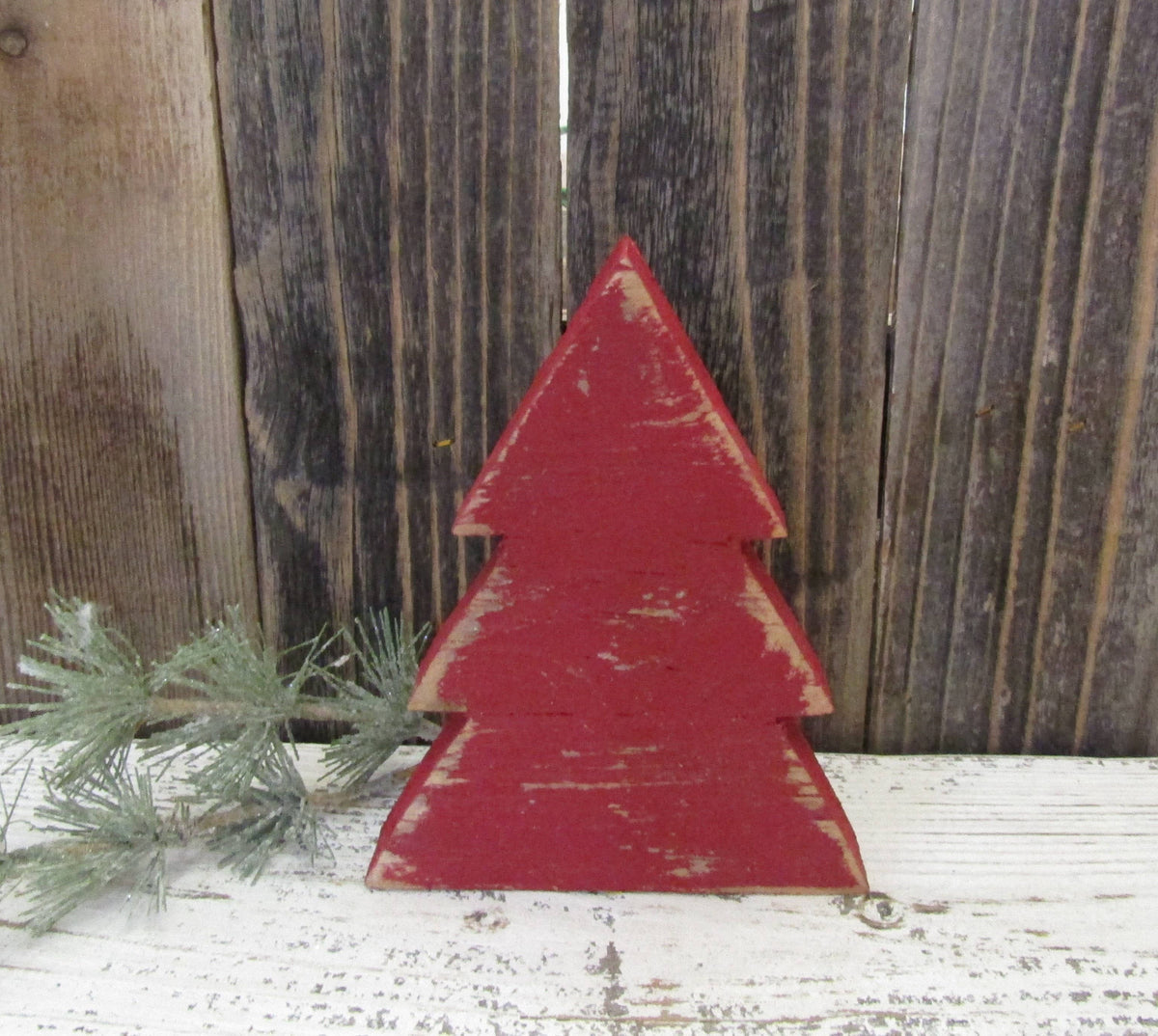 Red distressed wood Christmas tree shelf sitter against weathered barn wood