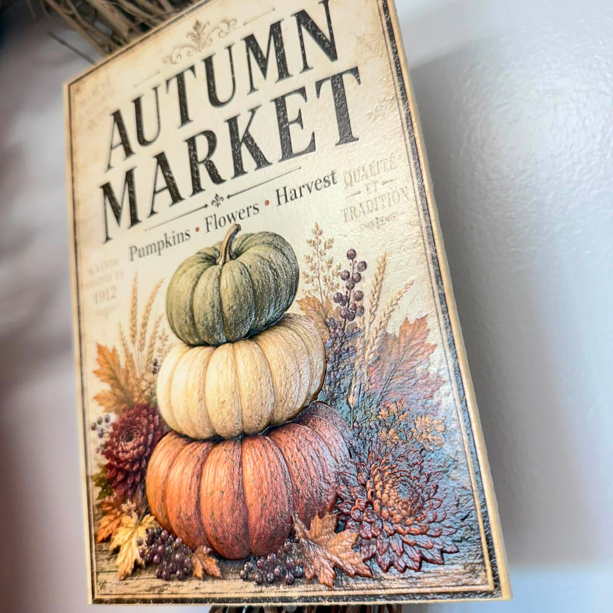 Close-up of the vintage Autumn Market sign with stacked pumpkins, mums and wheat