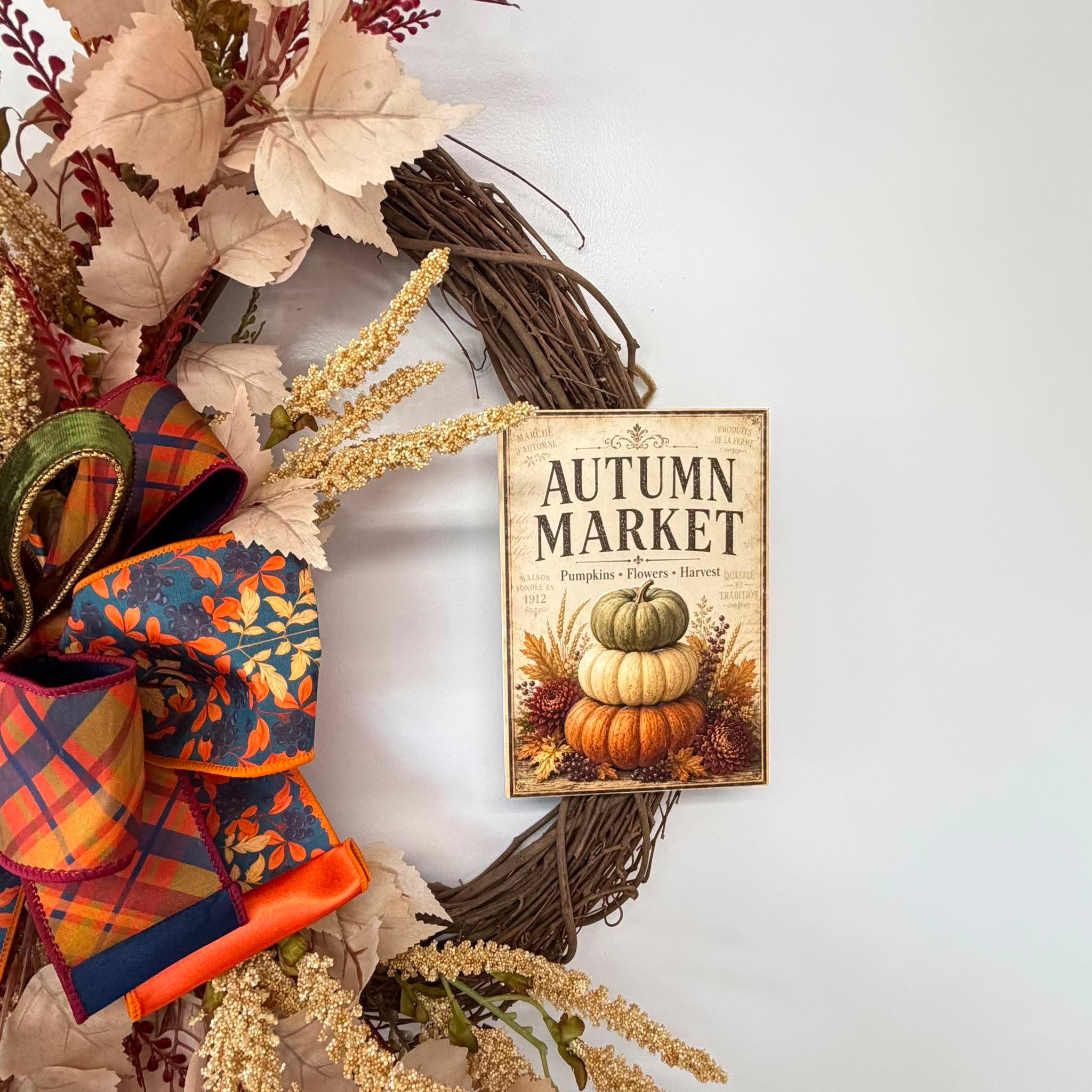 Close-up of the vintage Autumn Market sign reading Pumpkins, Flowers, Harvest above stacked pumpkins