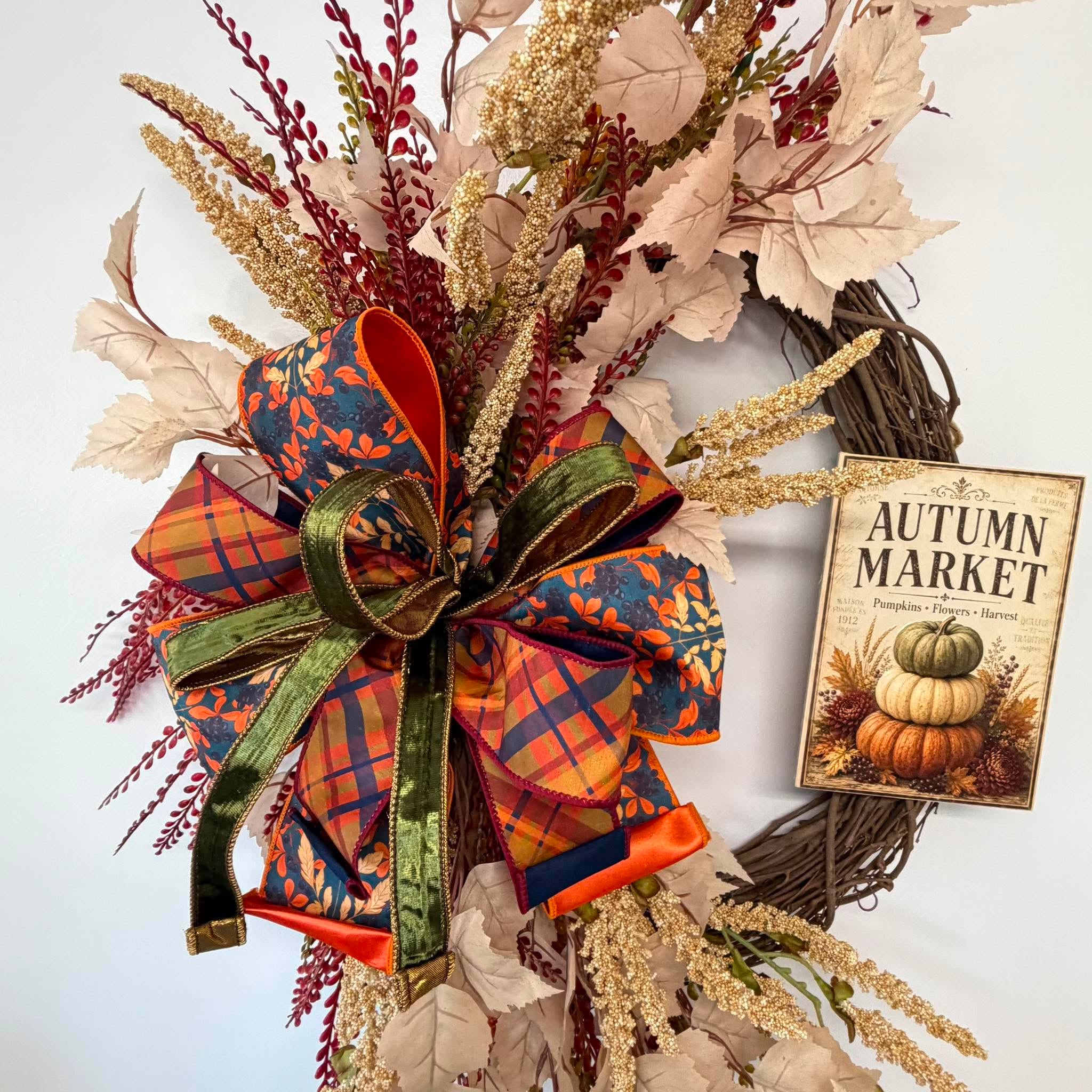Close-up of the layered orange plaid, teal leaf print and green velvet bow beside the Autumn Market sign
