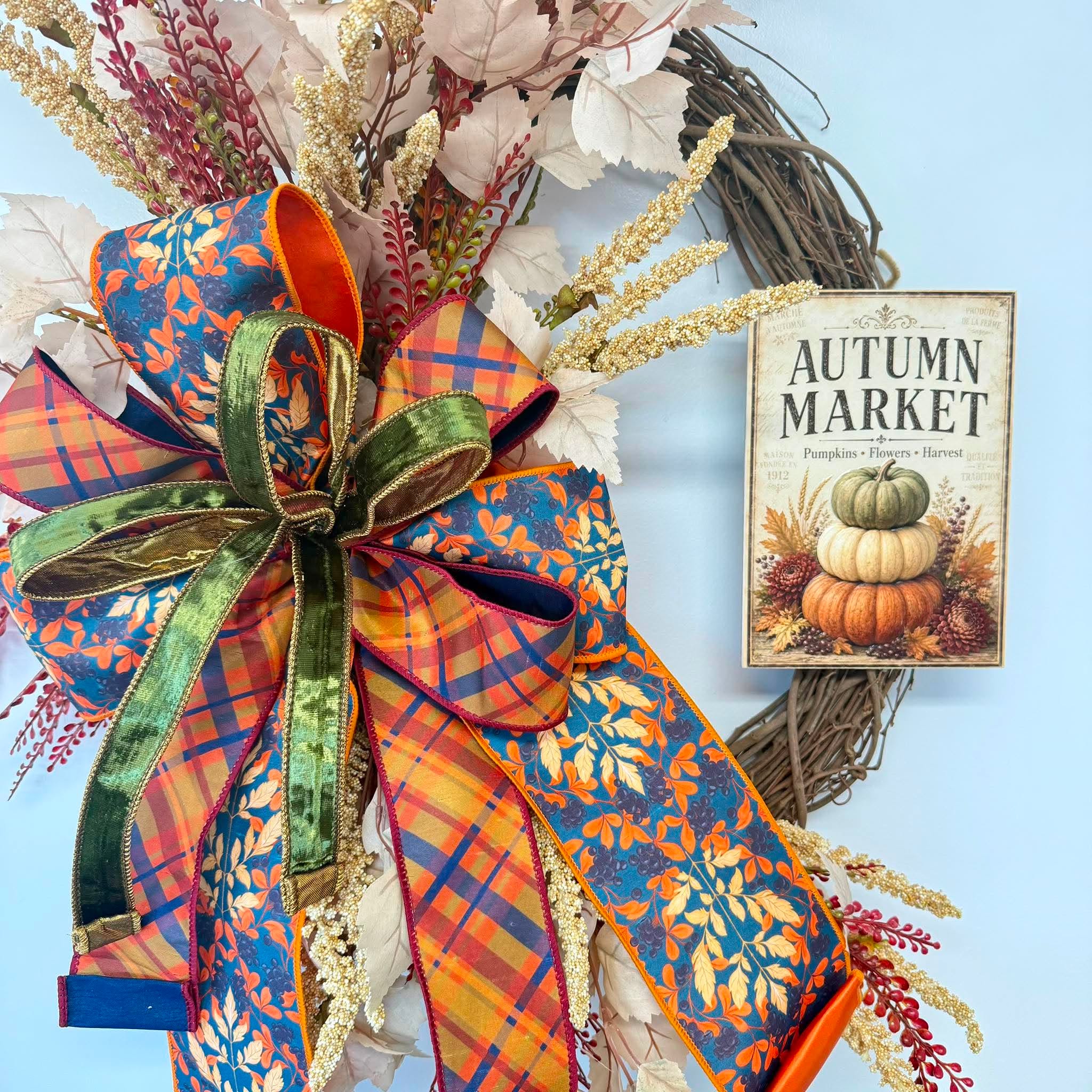 Close-up of the four-ribbon wired bow in orange plaid, teal leaf print, green velvet and orange satin