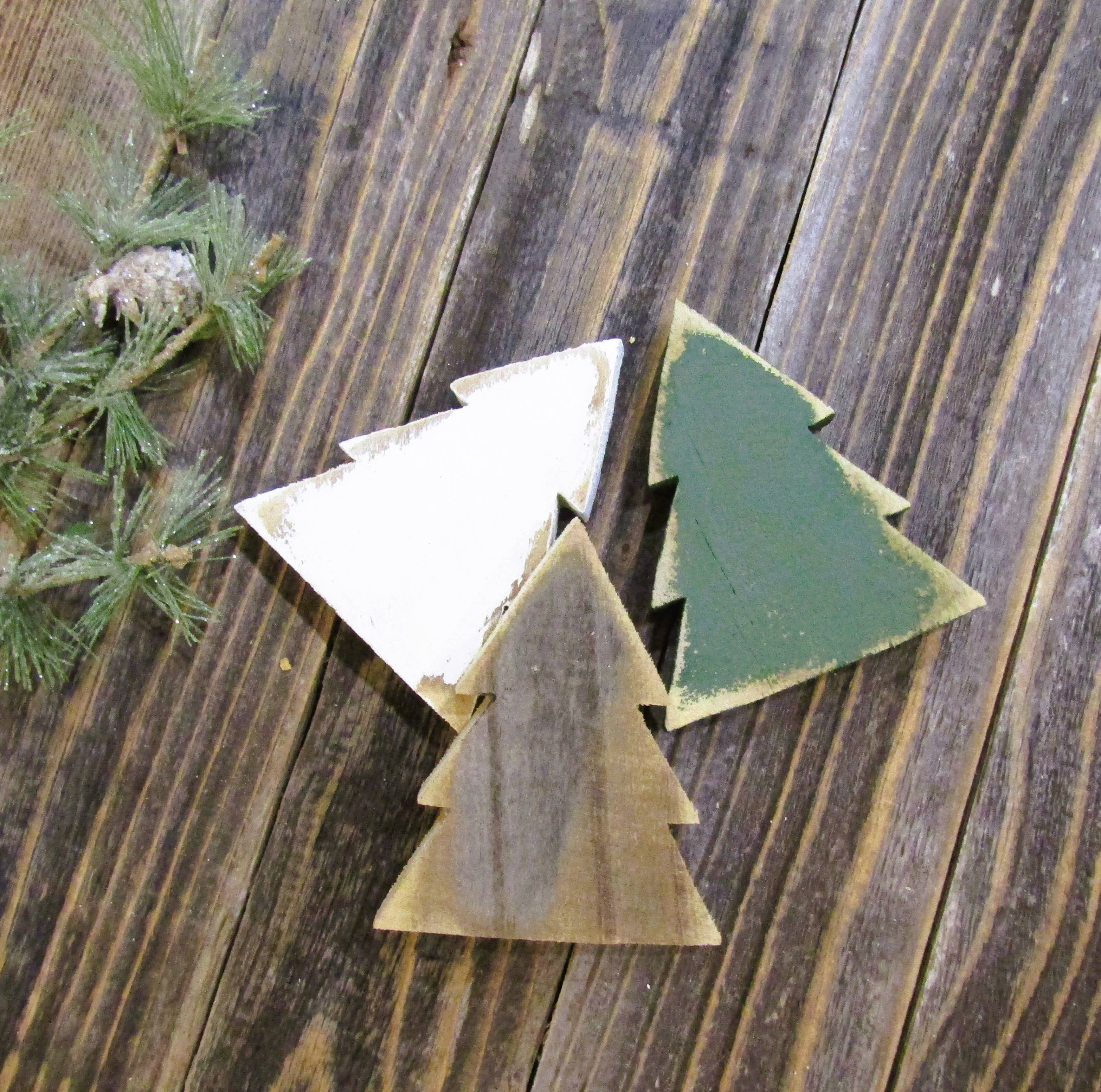 White, natural and green wood Christmas tree bowl fillers standing together on barn wood