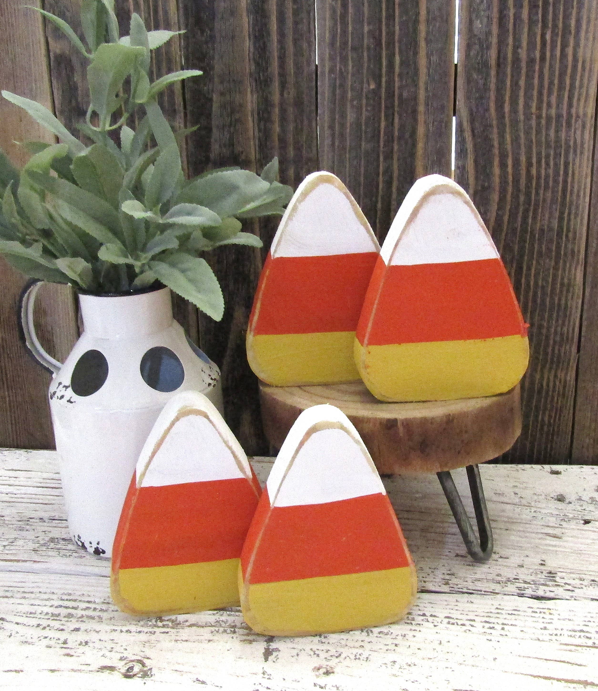 Chunky wood candy corn in white, orange and yellow beside a white farmhouse pitcher