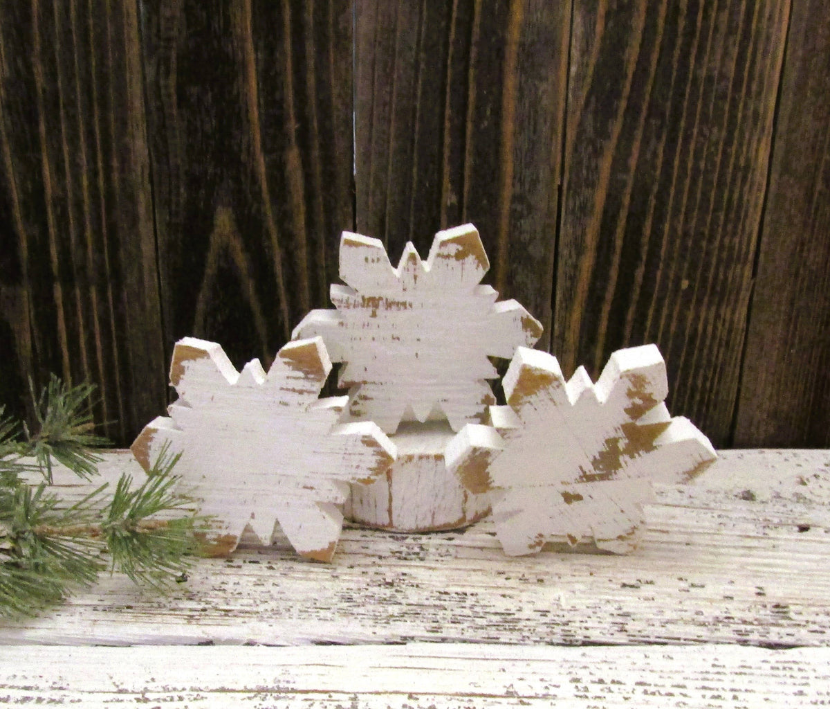 Cluster of rustic wood snowflake bowl fillers standing upright on a white farmhouse shelf