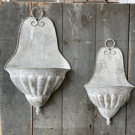 Two rustic metal wall sconces on a wooden panel background