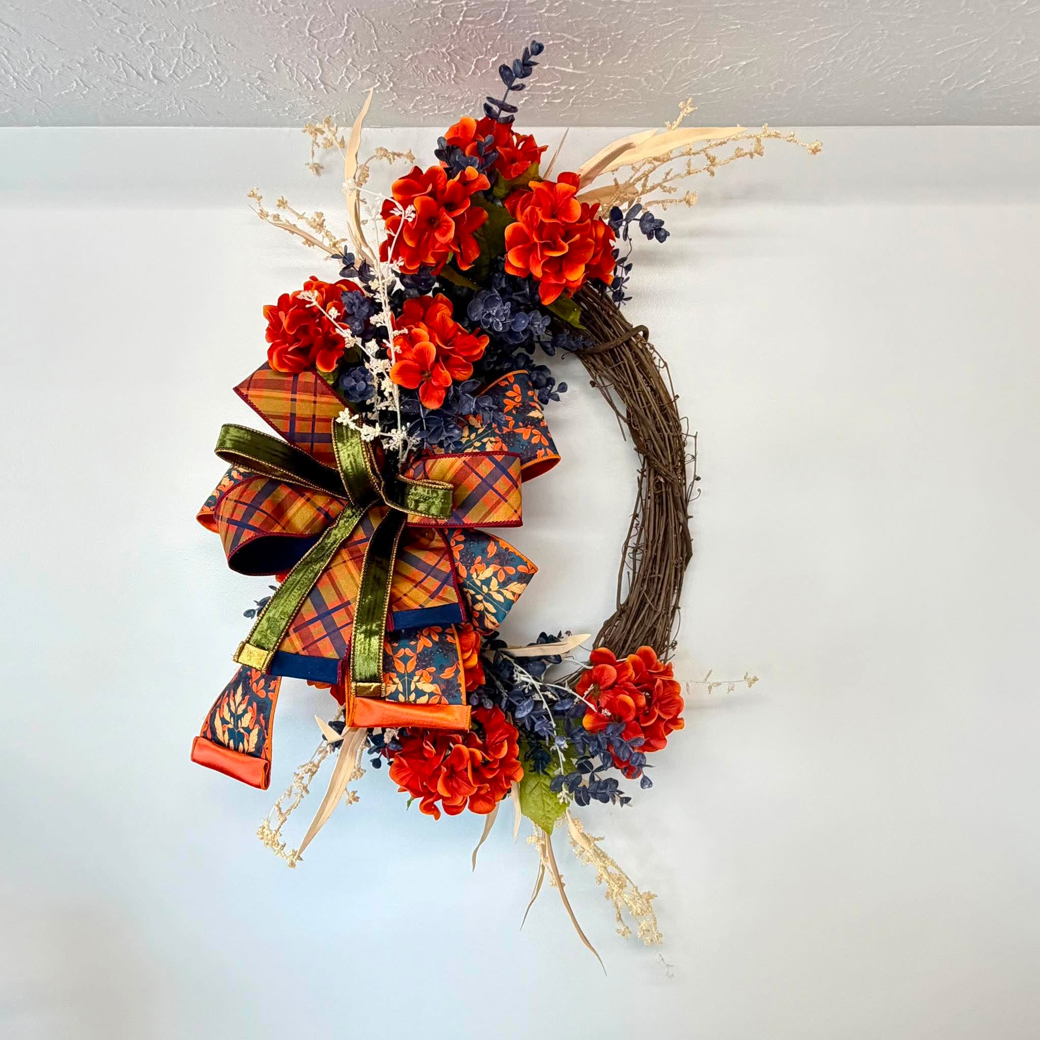Orange and navy blue hydrangea fall grapevine wreath hanging as front door decor