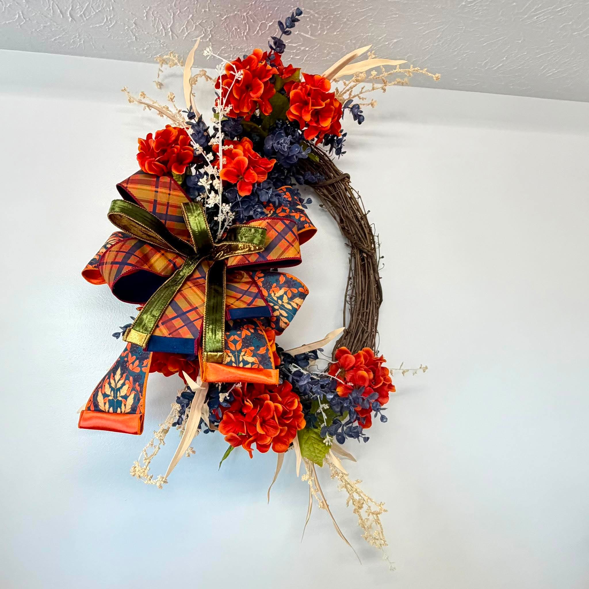 Burnt orange hydrangeas and navy blue berried eucalyptus sweeping across a grapevine wreath