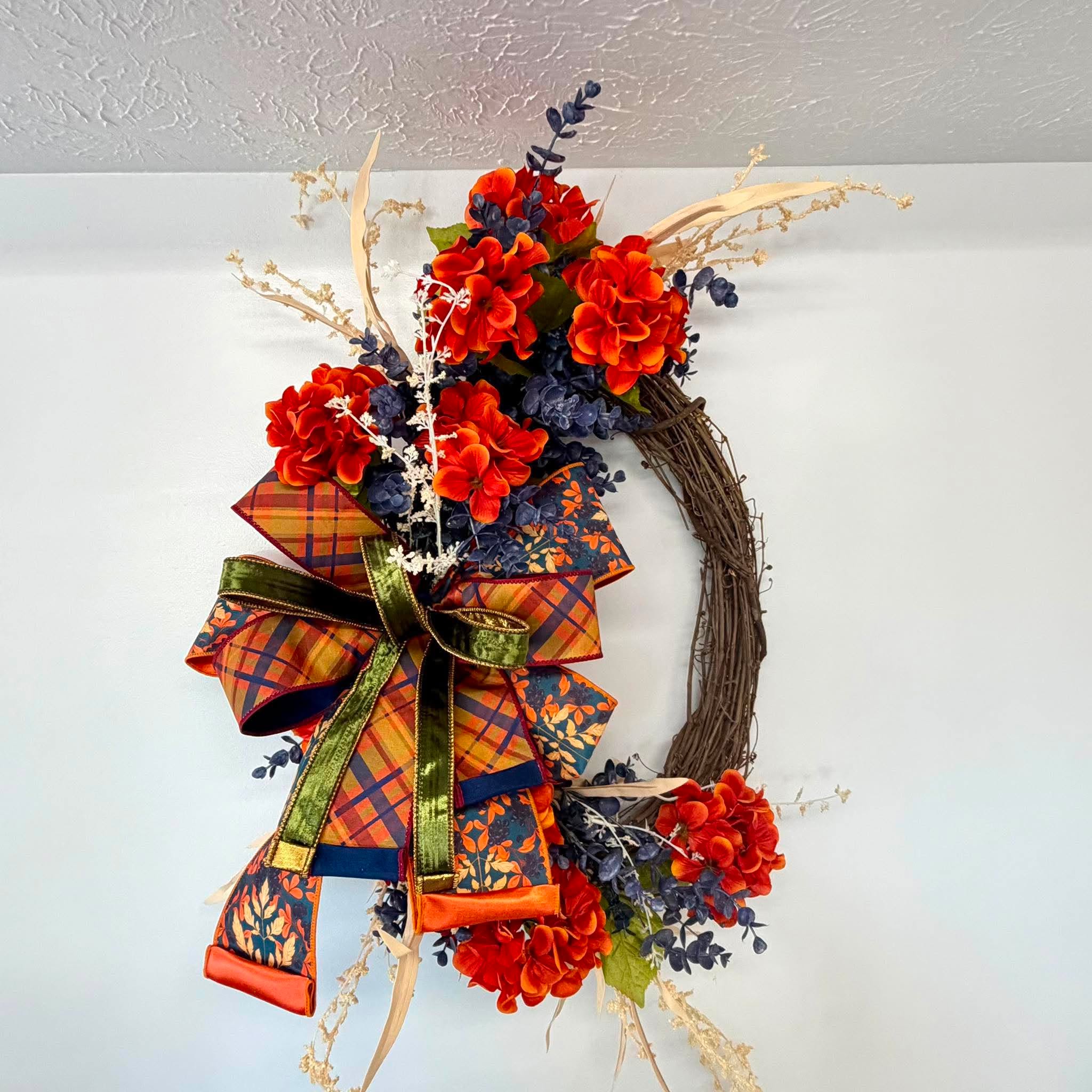 Close-up of the orange plaid and teal leaf print ribbon bow on the orange and navy fall wreath