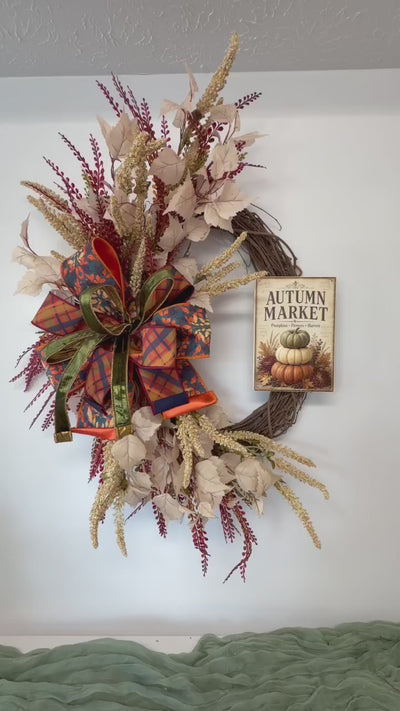 Video of the Autumn Market fall grapevine wreath styled on a wall above a sage green runner