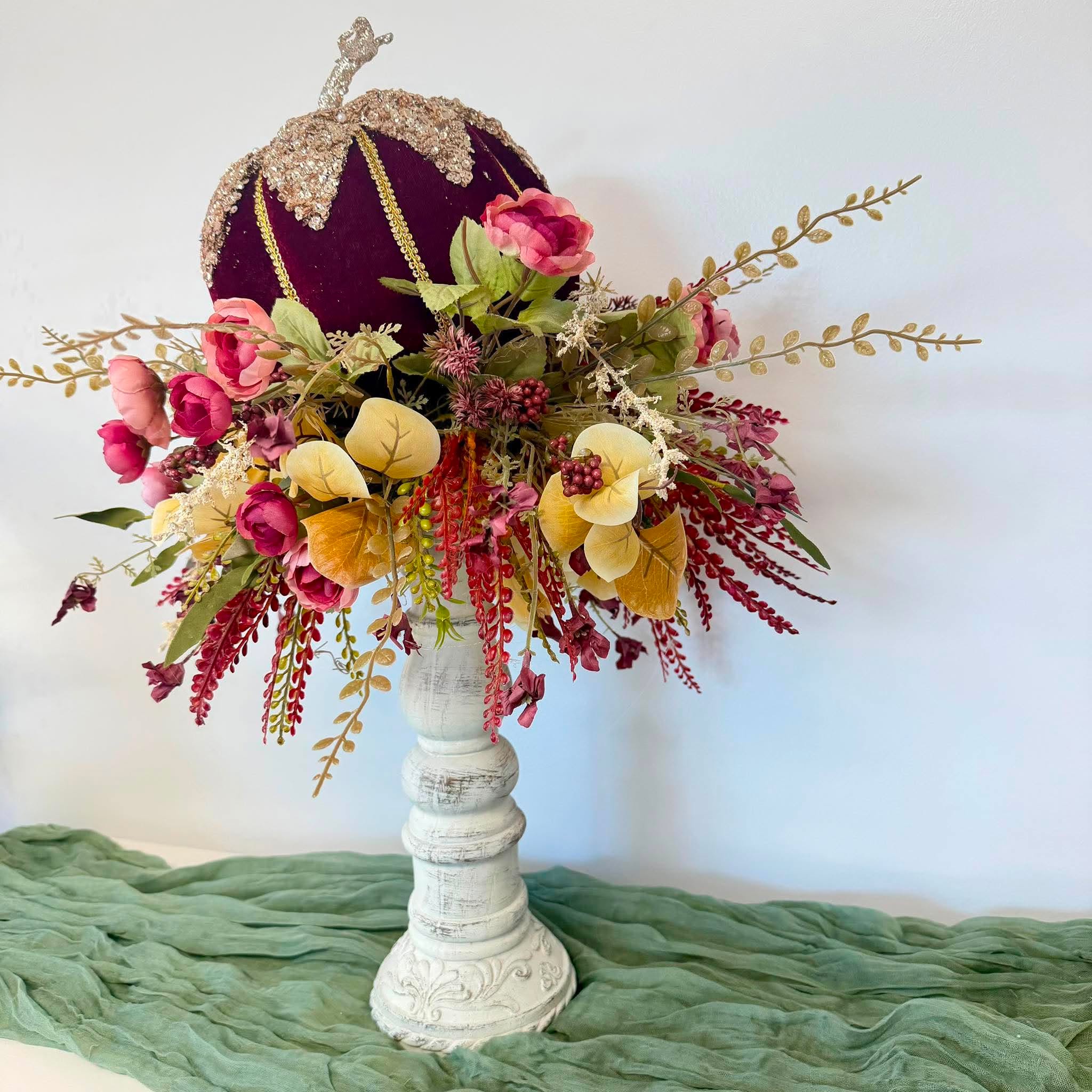 Close-up of pink and magenta roses, cream astilbe and gold eucalyptus beneath the velvet pumpkin